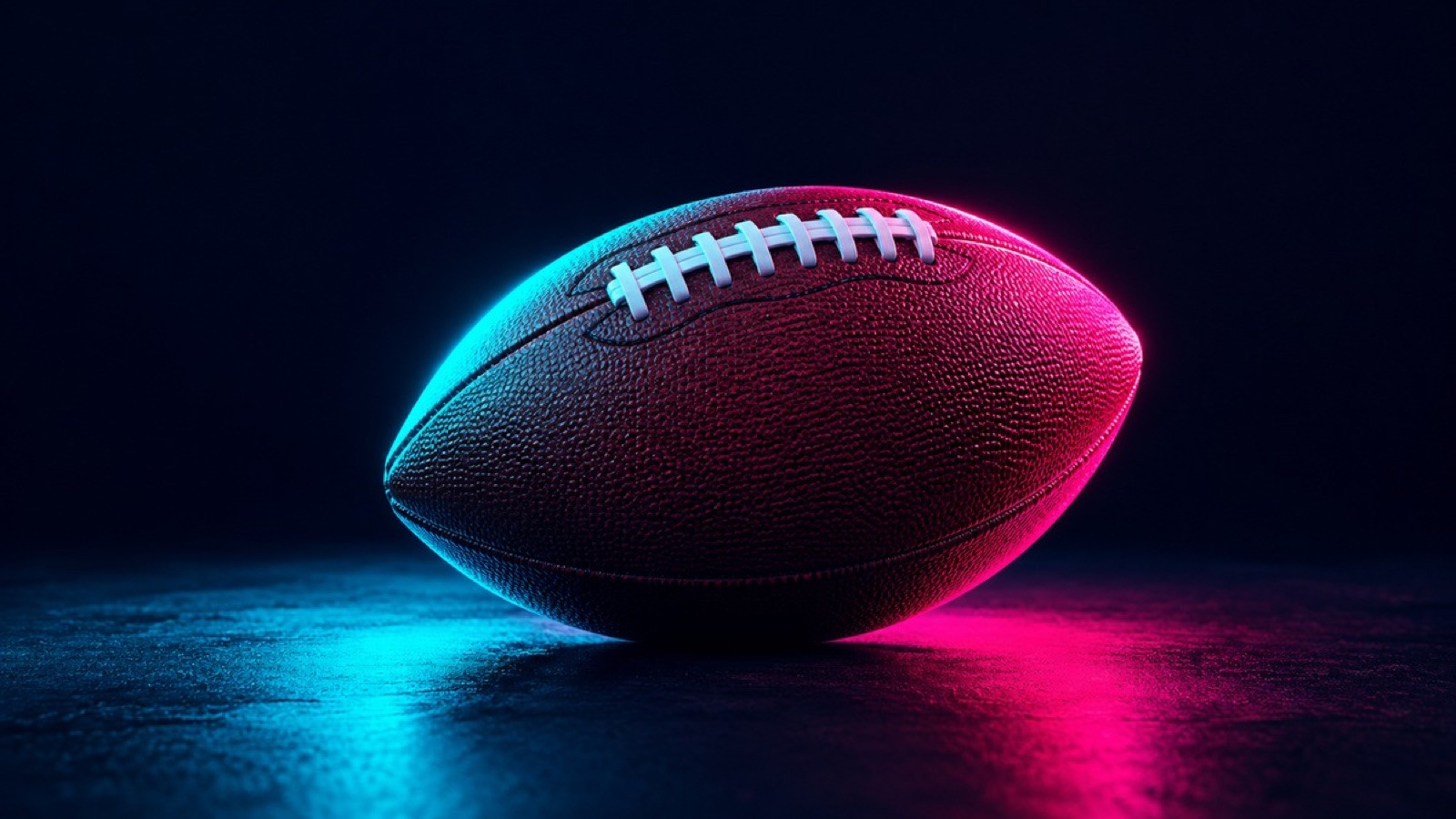 A brown American football with white laces rests on a dark surface.